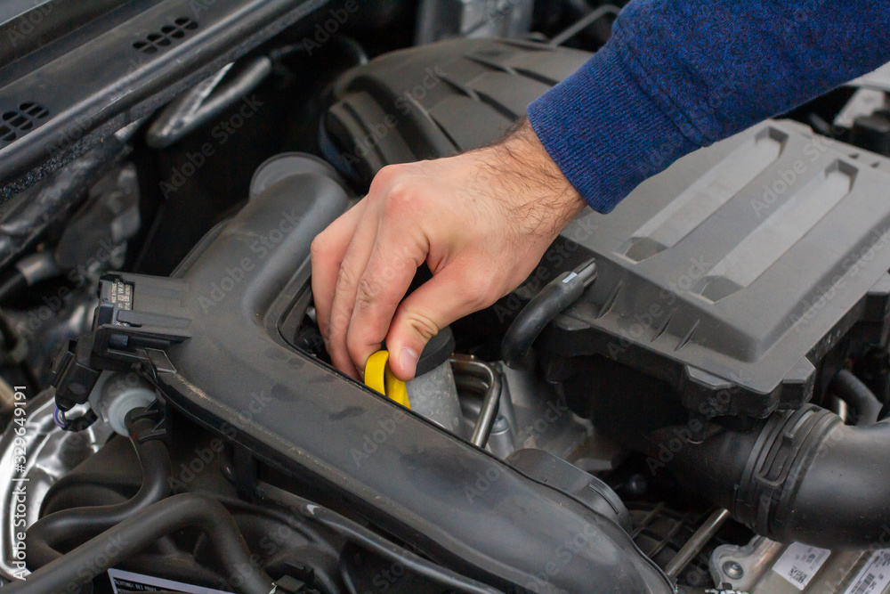 Closeup of mechanic hands checking motor under the hood in the broken car. Repairing of the vehicle concept. Automobile service Closeup of mechanic hands checking motor under the hood in the broken car. Repairing of the vehicle concept. Automobile service