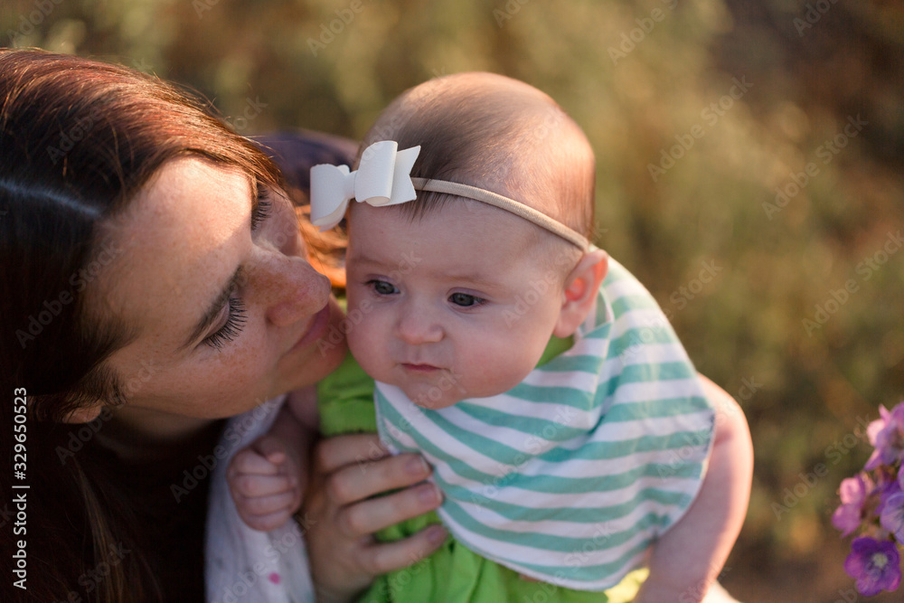 A mother and her baby stop and smell the flowers on an outdoor hike. A mother and her baby stop and smell the flowers on an outdoor hike.