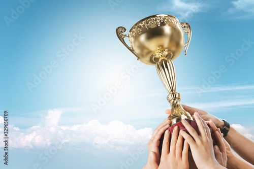 Hands holding a champion golden trophy on sky background photo