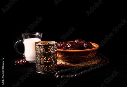 Ramadan lamp and dates with cup of milk, still life on a black background.