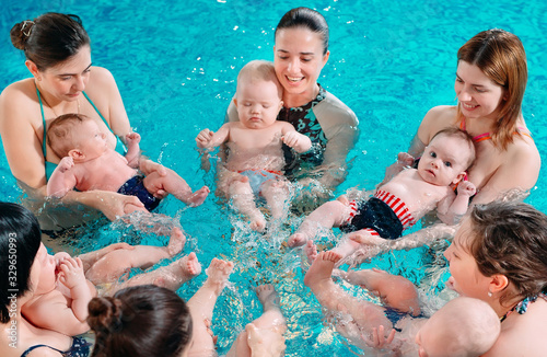 Obraz na plátně A group of mothers with their young children in a children's swimming class with a coach