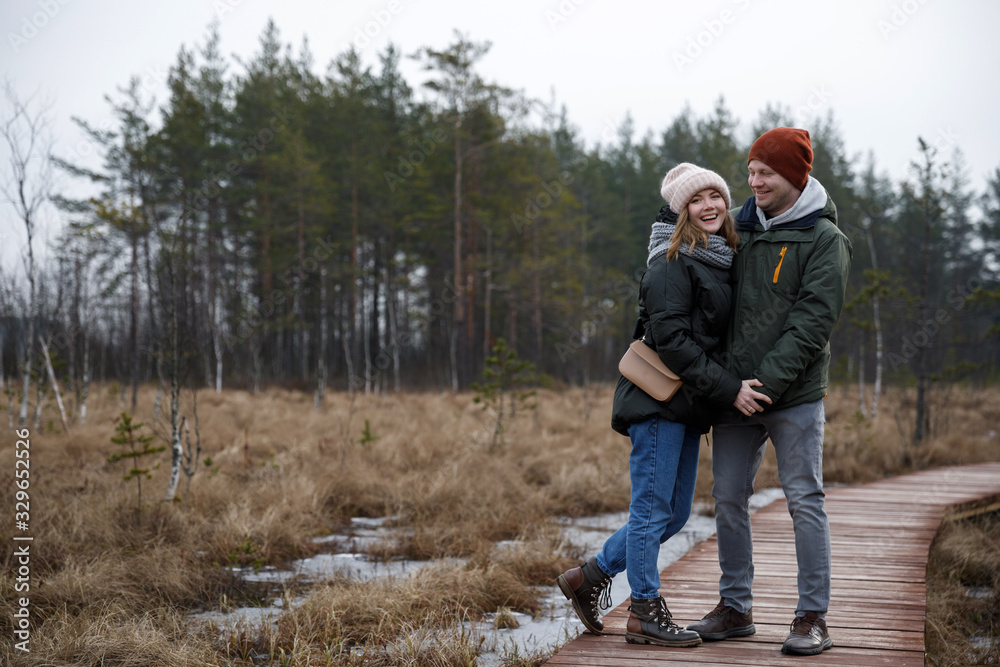 couple on a walk in the woods. Girl and boyfriend walk in nature in jackets and hats.