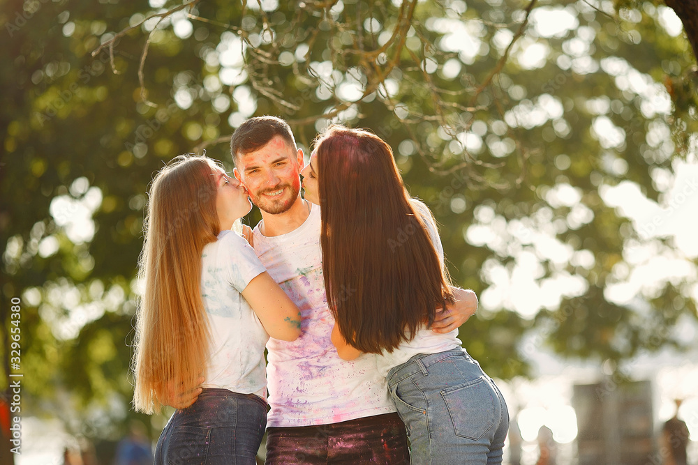 Fototapeta premium Friends with a holi paints. People in a summer park. Students have fun.