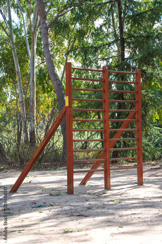 View of wooden apparatus for training in a sports area of a park with trees, in Madrid, Spain. Vertically View of wooden apparatus for training in a sports area of a park with trees, in Madrid, Spain. Vertically