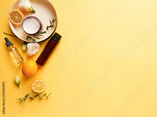 flatlay composition with cream, lotion, oil, flower, citrus and eucalyptus on yellow background. Concept beauty natural vitamin cosmetic product, skin care, copyspace, top view