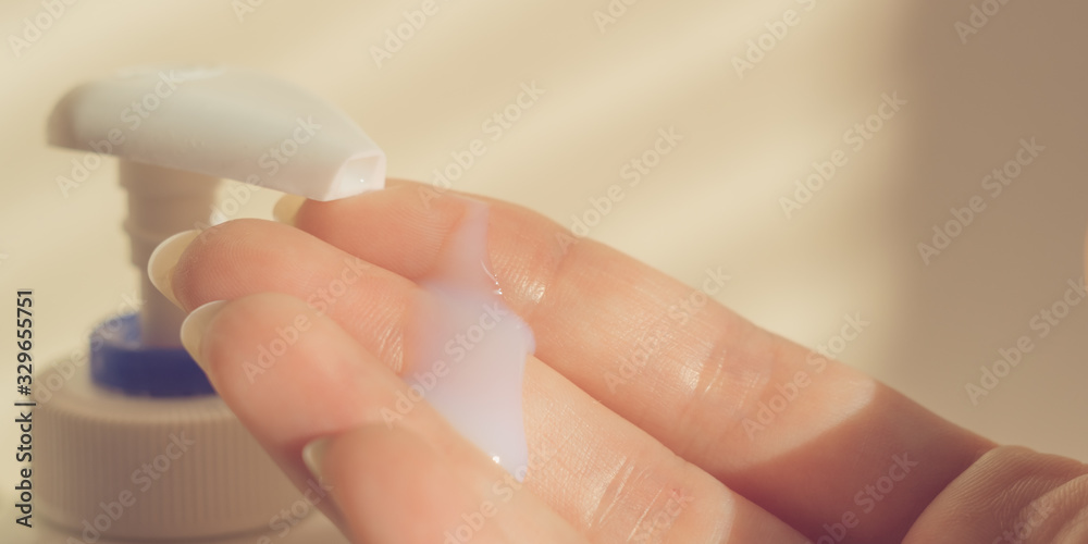 A female hand uses liquid soap with a dispenser. White gel on the human fingers. A female hand uses liquid soap with a dispenser. White gel on the human fingers.