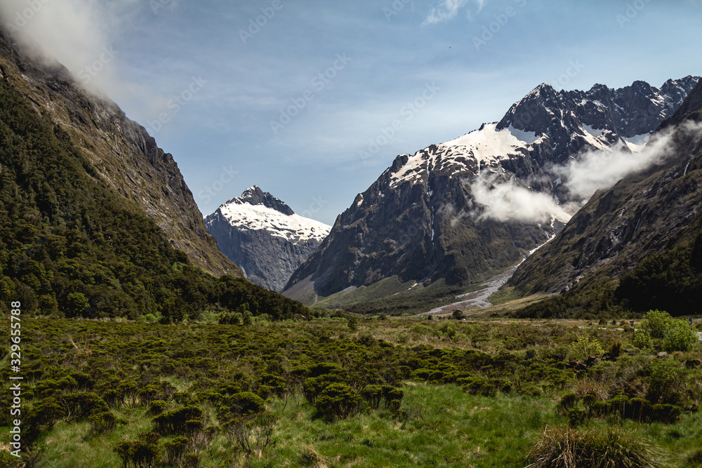 Green fields and snowcapped mountains in Fiordland National Park, New Zealand