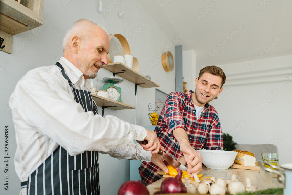 Young man and his father cooking in kitchen Young man and his father cooking in kitchen
