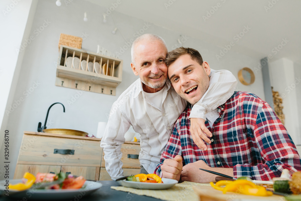 Happy adult son and senior father hugging at home Happy adult son and senior father hugging at home