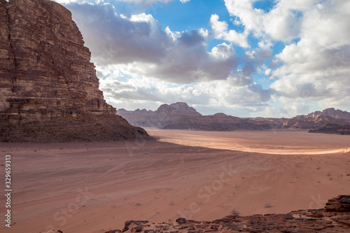 Kingdom of Jordan, Wadi Rum desert, sunny winter day scenery landscape with white puffy clouds and warm colors. Lovely travel photography. Beautiful desert could be explored on safari. Miniature car
