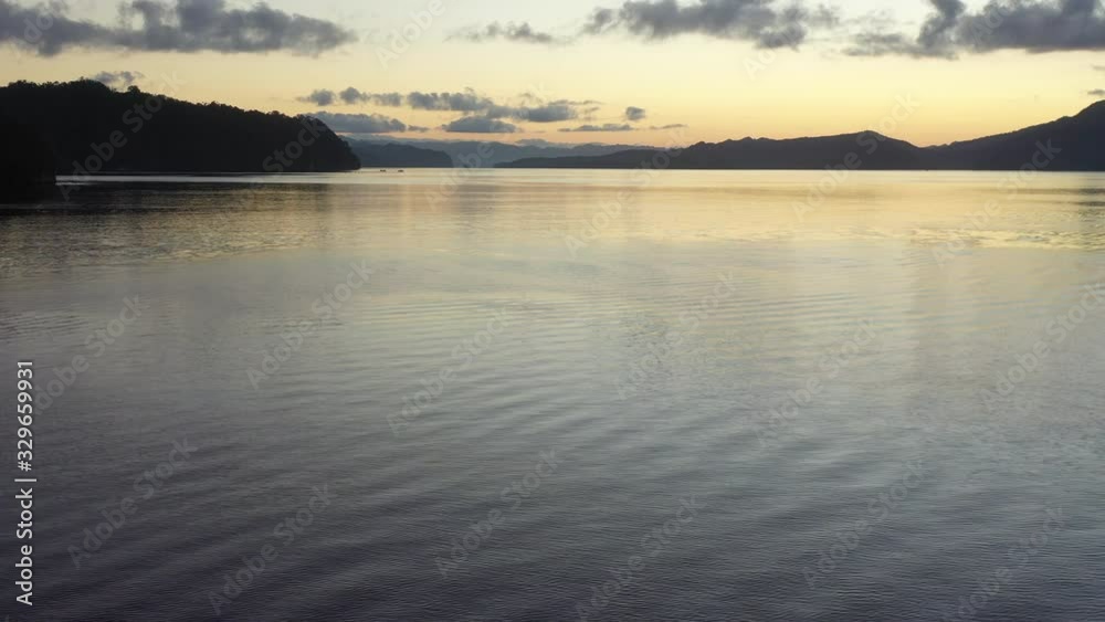 A serene dawn illuminates the calm waters of Alyui Bay in Raja Ampat, Indonesia. This remote, equatorial area is known for its extraordinary marine biodiversity. A serene dawn illuminates the calm waters of Alyui Bay in Raja Ampat, Indonesia. This remote, equatorial area is known for its extraordinary marine biodiversity.