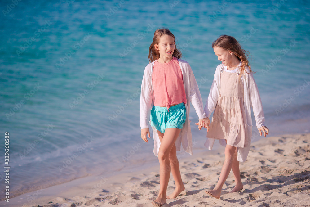 Little happy funny girls have a lot of fun at tropical beach playing together. Little happy funny girls have a lot of fun at tropical beach playing together.