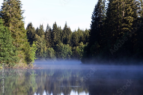 Morning haze over surface of the Pohorsky pond know as Jiricka reservoir near Pohorska Ves, Novohradske Mountains, Cesky Krumlov District, South Bohemian Region, Czech Repubic, sunny summer day