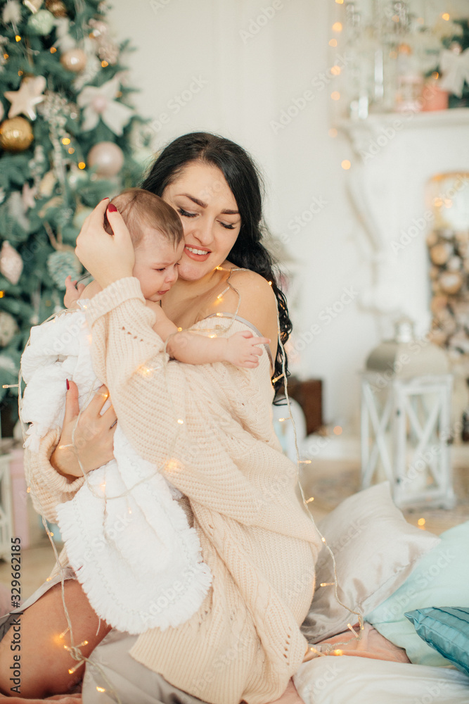 Baby girl and mother near Christmas tree Baby girl and mother near Christmas tree
