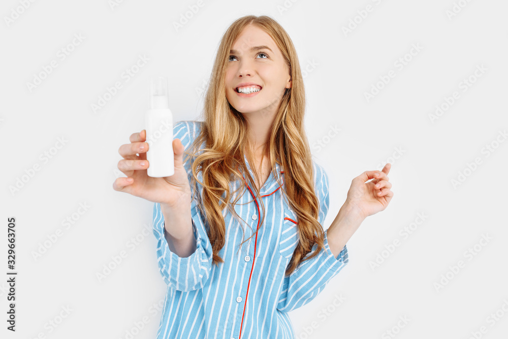 Portrait of happy beautiful young woman in pajamas standing isolated on white background applying face lotion Portrait of happy beautiful young woman in pajamas standing isolated on white background applying face lotion