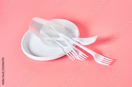 Disposable plastic utensils on pink background. Concept of save environment  ecology  recreation on picnic  party and other events
