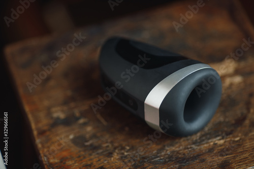 Sex toy for men. Artificial vagina for masturbation. A black sex toy for fap lies on a wooden table top. Sex shop for adults. Penis stimulator.