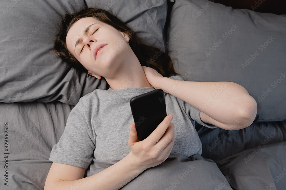 Fibromyalgia concept. Top view of unhappy young woman lying in bed in