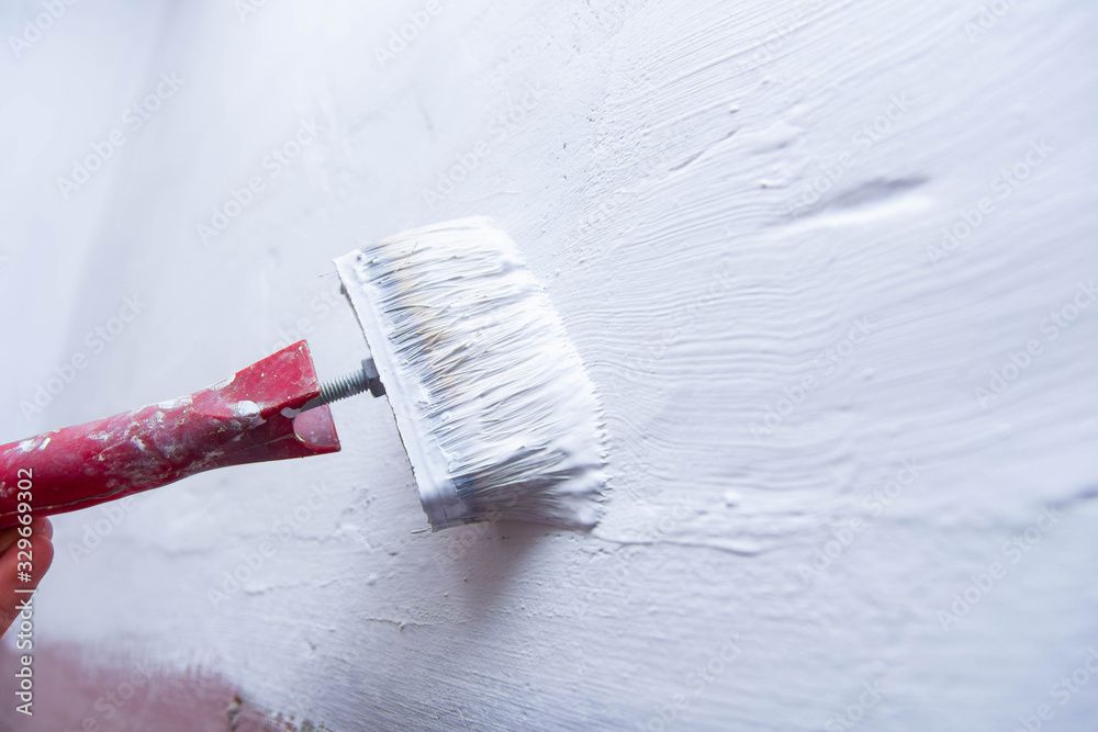 paint brush with a white paint primer - wall painting, apartment repair.