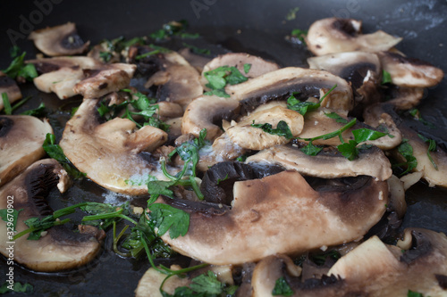 Mushrooms frying in a pan with fresh coriander