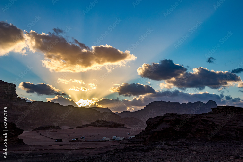 Obraz premium Kingdom of Jordan, Wadi Rum desert, impressive sunset sky and light over desert in darkness and shadows. Lovely travel photography. Beautiful desert could be explored on safari. Colorful image