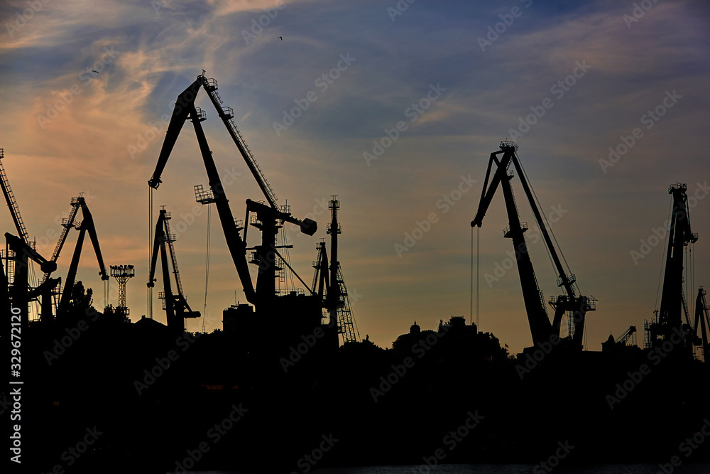 Harbor cranes in backlight. Port cranes at industrial sea port Harbor cranes in backlight. Port cranes at industrial sea port