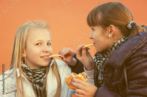 Happy teen girls eating a burgers and french fries
