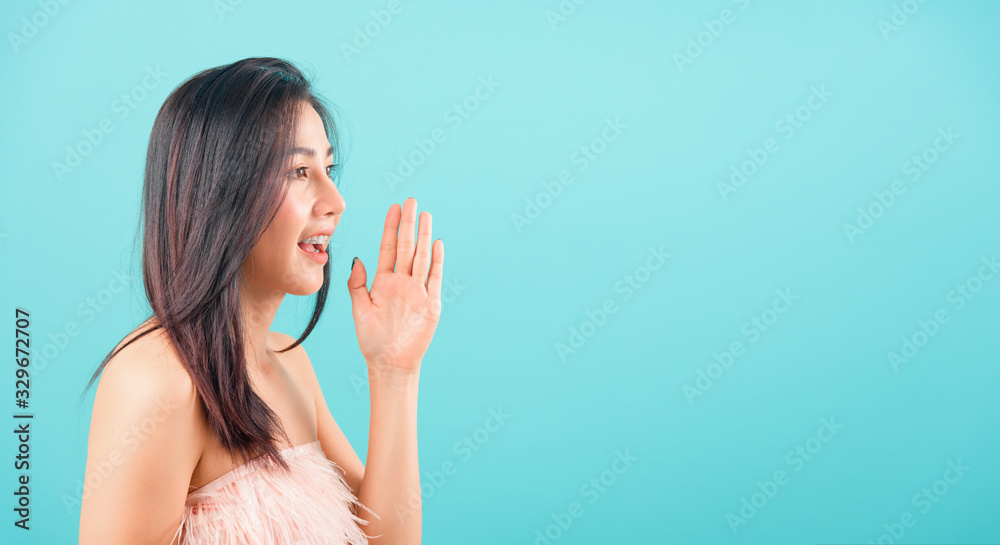 Portrait asian beautiful woman smiling and hand beside mouth telling somthing her eyes looking out Portrait asian beautiful woman smiling and hand beside mouth telling somthing her eyes looking out