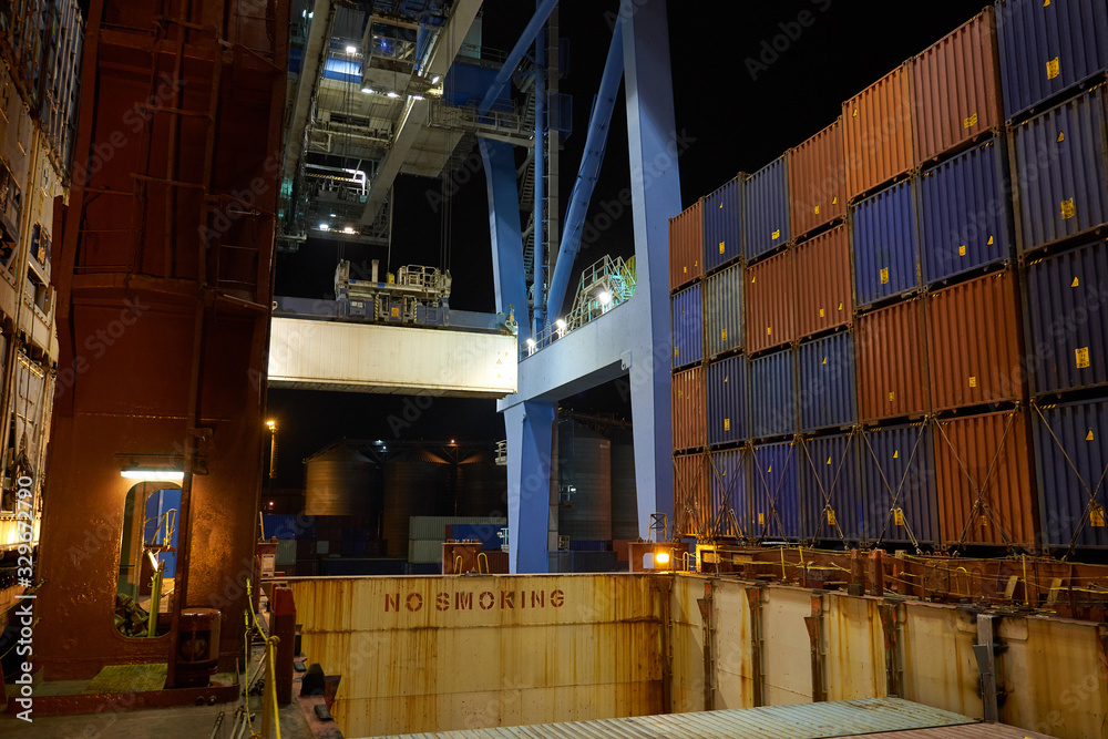 Container ship in port at container terminal. Ships of container ships stand in terminal of port on loading, unloading container at night time.