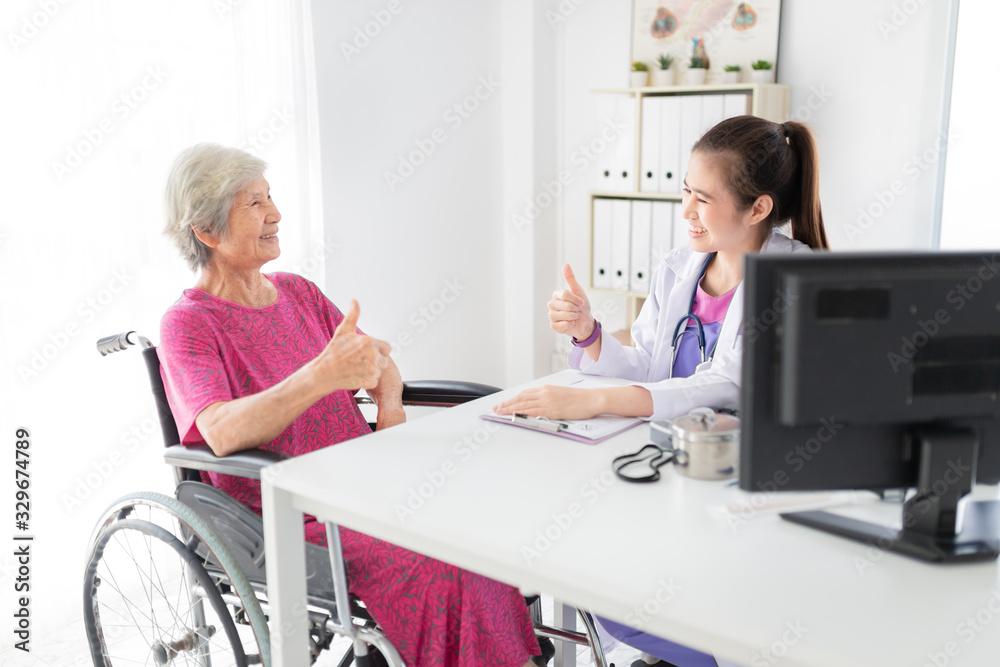 Asian doctor talk with old female patient about disease symptom, they show thumbs up sign with hand together, elderly health check up, happiness hospital