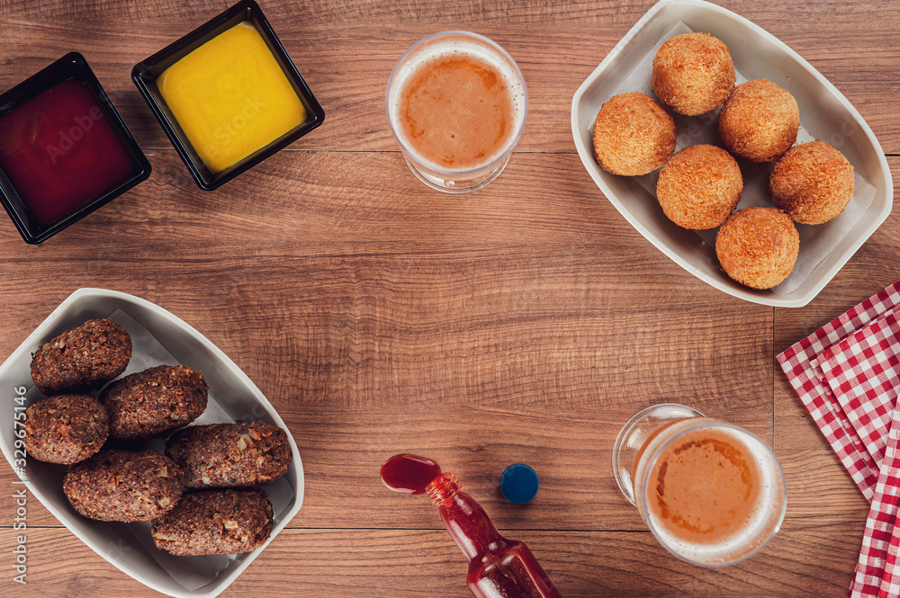 Top view of table with beer, brazilian appetiser coxinha de frango and kibbe