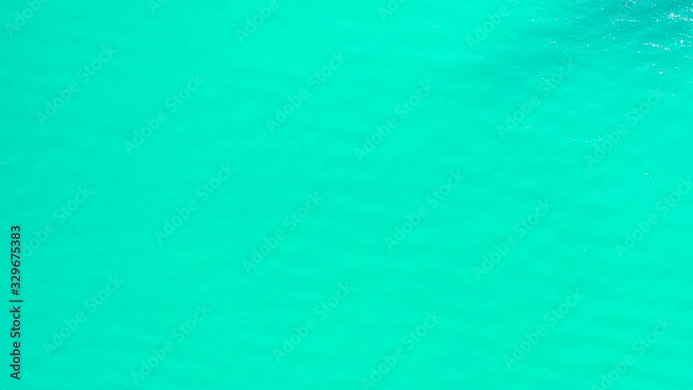 Turquoise sea texture with minimalist abstract pattern of clear vibrant water reflecting sunlight on blurry surface, copy space
