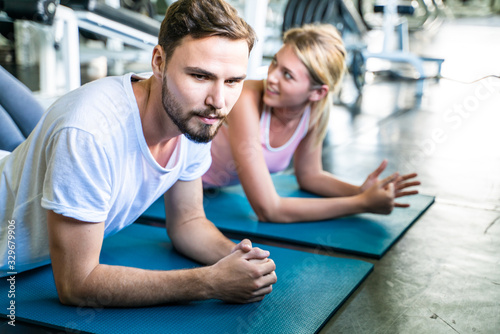 Sport men and women exercise planking on yoga mat in sport gym together