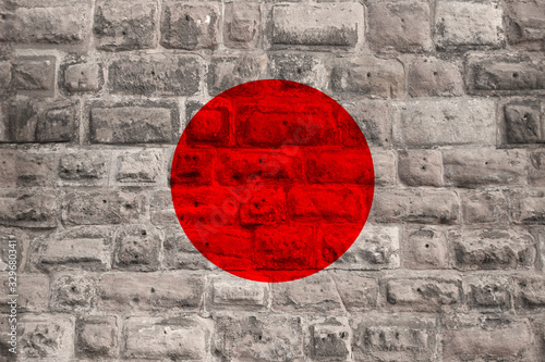 national flag of the modern state of Japan on an old historical stone wall, the concept of business, tourism, travel, emigration, globalization