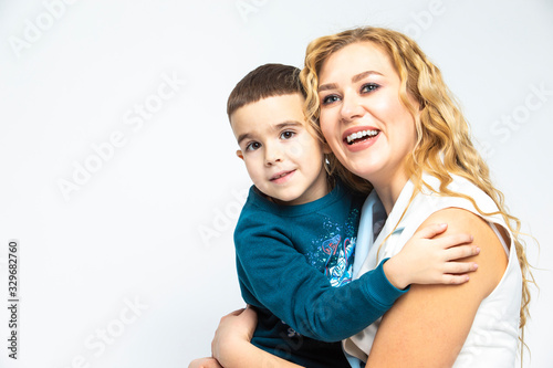 Portrait of Happy Loving Caucasian Mother With Her Son in Studio Indoors. Posing Against White Background