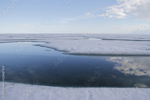 Broken pans of sea ice on ocean coast with blue sky and clouds along the Northwest Passage in June  Cambridge Bay  Nunavut