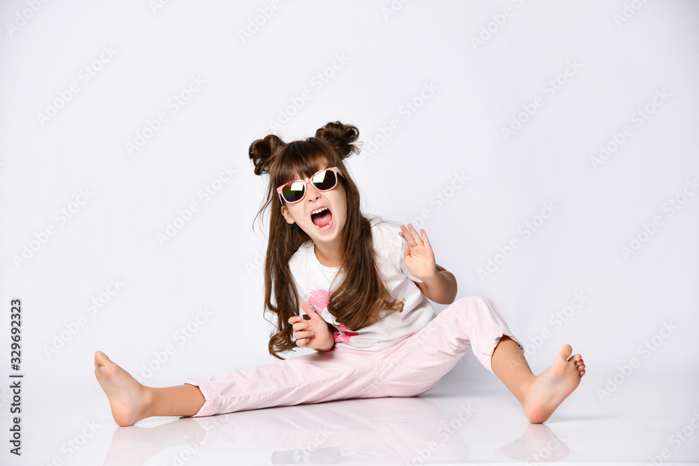 Girl pose sitting on the floor, in the Studio, in sunglasses and fashionable hairstyle, barefoot