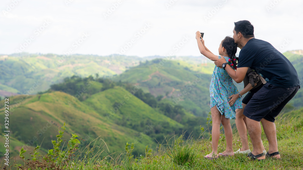 Family  of father mother and daughter taking selfie on the top of mountain.16:9 style