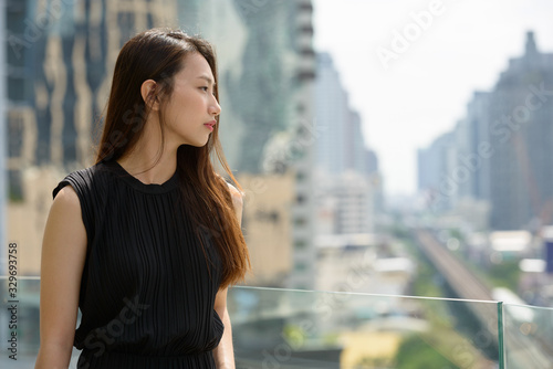 Young beautiful Asian businesswoman against view of the city