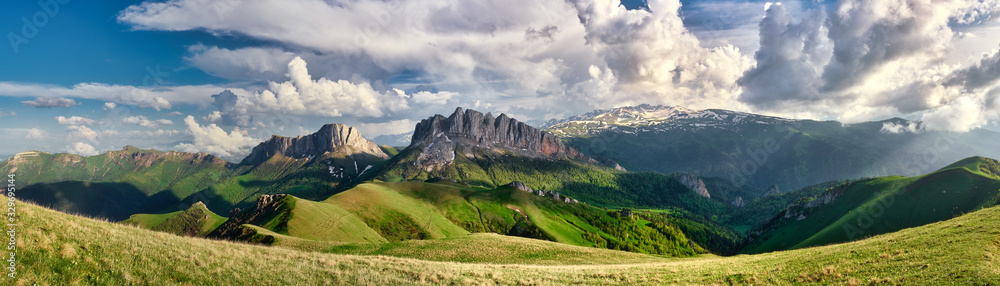 Naklejka premium sun spots on meadow landscape with clouds. The formation and movement of clouds over the summer slopes of Adygea, Bolshoy Tkhach and the Caucasus Mountains 