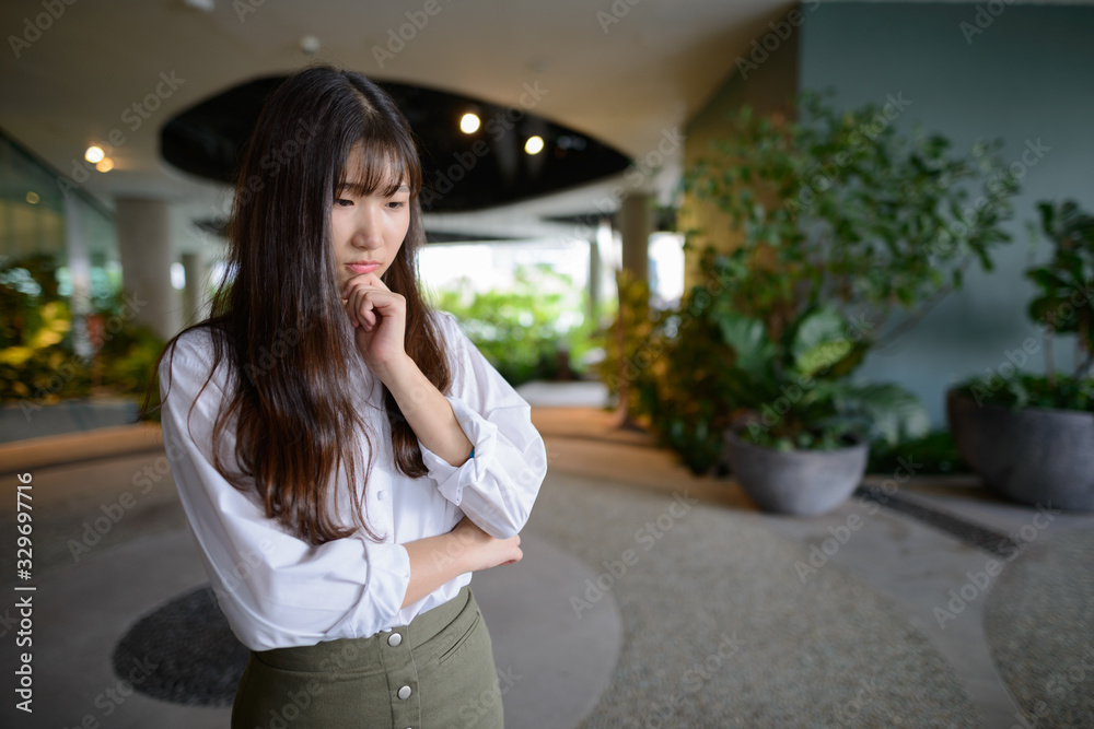 Young beautiful Asian teenage girl thinking at the indoor garden