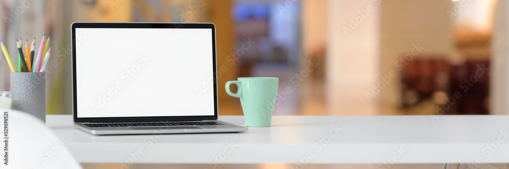 Cropped shot of simple workspace with blank screen laptop, mug, stationery and copy space Cropped shot of simple workspace with blank screen laptop, mug, stationery and copy space