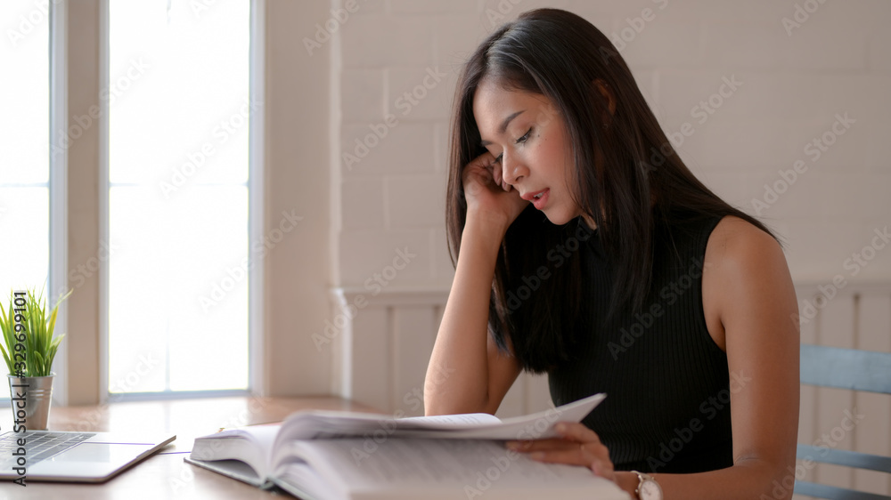 Close up view of young college girl focusing on book to prepare her project Close up view of young college girl focusing on book to prepare her project