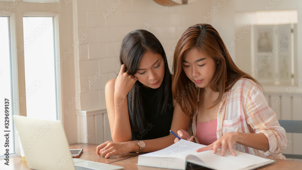 Cropped shot of two young college girl reading together Cropped shot of two young college girl reading together