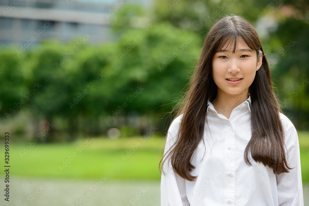 Happy young beautiful Asian teenage girl at the park