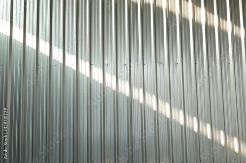 Aluminum wall surface with sunlight that creates shadows on the wall during the day.