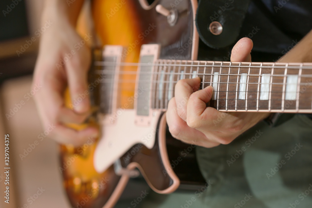 Fototapeta premium Young man playing guitar, closeup