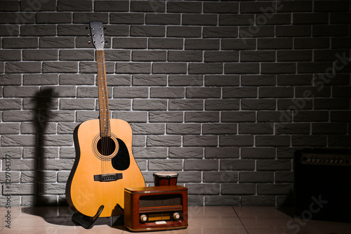 Modern guitar, drum and radio receiver near brick wall