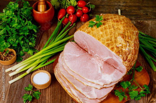 Dinning table with whole baked and sliced ham, vegetables and spice.