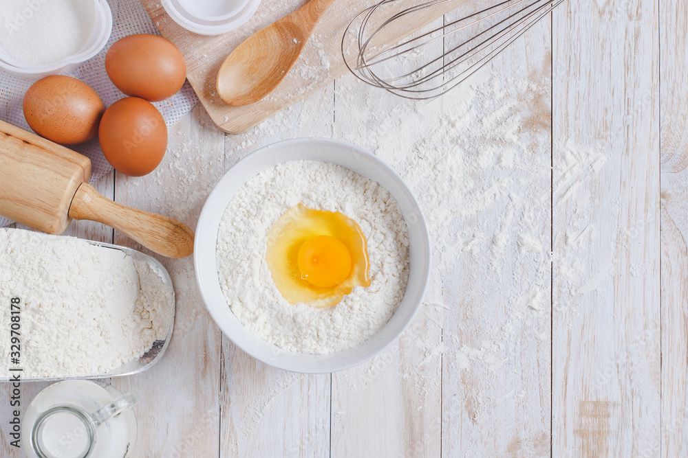 Homemade Dough Recipe (Eggs, flour, milk, sugar) and wooden kneading dough on a wooden table, view from above